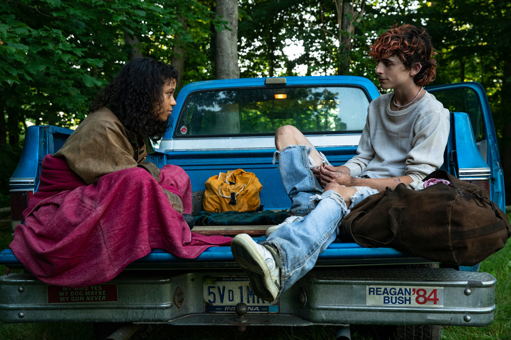 Eine junge Frau und ein junger Mann sitzen auf der Ladefläche eines Pickups.