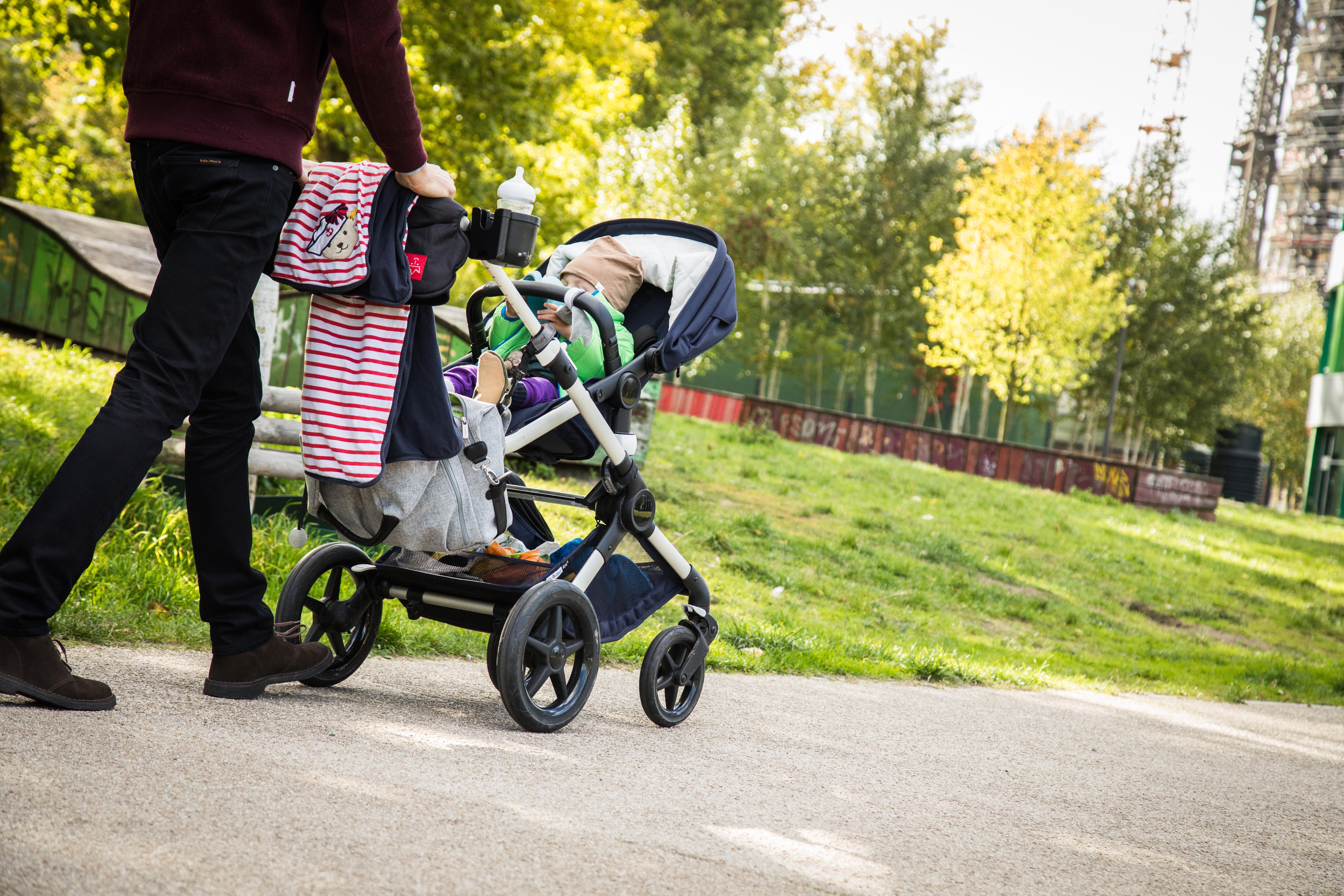 Vater geht mit einem Kinderwagen spazieren (Symbolbild).