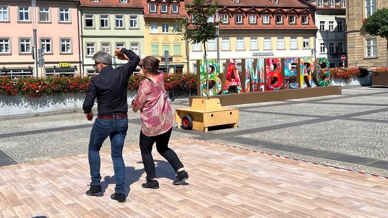 Menschen tanzen auf einem Tanzboden auf dem Bamberger Maxplatz. 