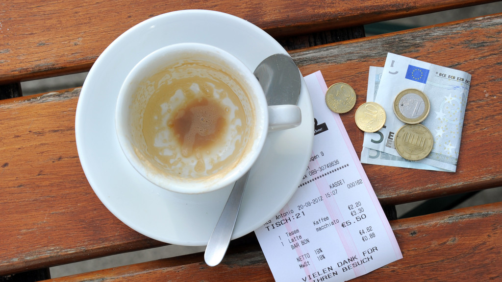 Münzen, ein Geldschein und eine Rechnung liegen neben einer leeren Kaffeetasse auf einem Tisch in einem Restaurant (Archivbild)