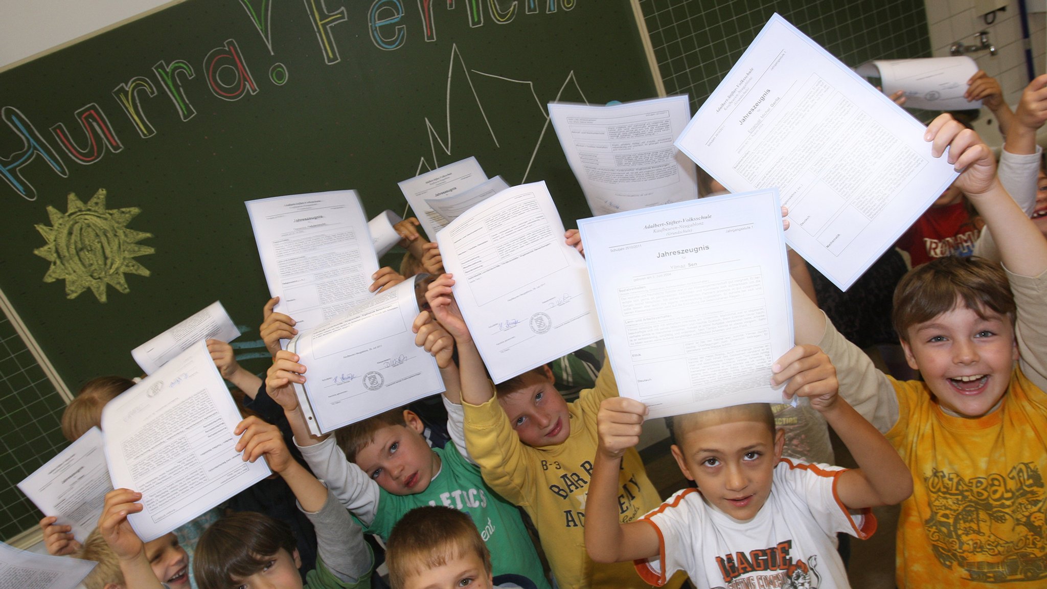 Kinder halten ihre Zeugnisse hoch