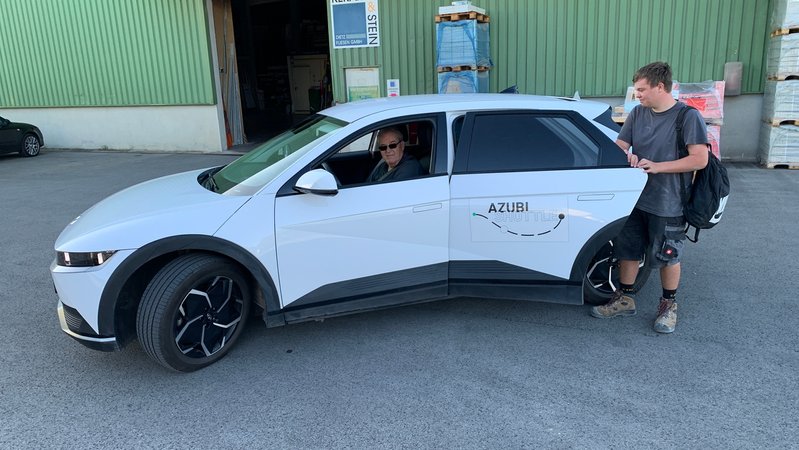 Vor einer Betriebshalle steigt ein junger Handwerker in ein Azubi-Shuttle ein. Der Fahrer blickt aus dem Fenster. | Bild: BR / Norbert Steiche Vor einer Betriebshalle steigt ein junger Handwerker in ein Azubi-Shuttle ein. Der Fahrer blickt aus dem Fenster.