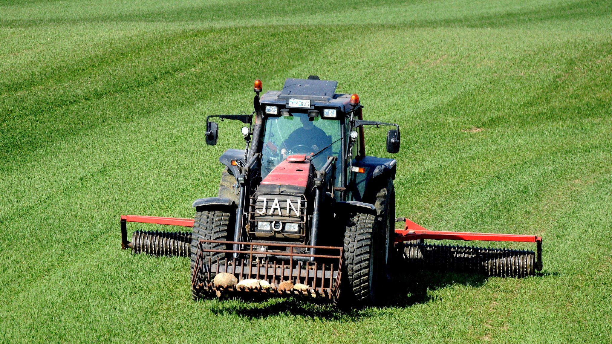 Ein Traktor mit einer Walze bei der Arbeit auf einem grünen Feld (Archivbild)