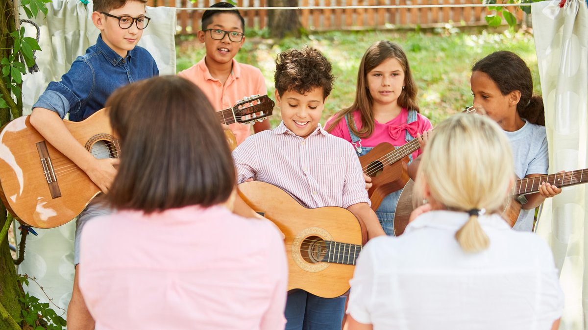 Kinder Gruppe mit Gitarren beim Talentshow Auftritt im Ferienlager