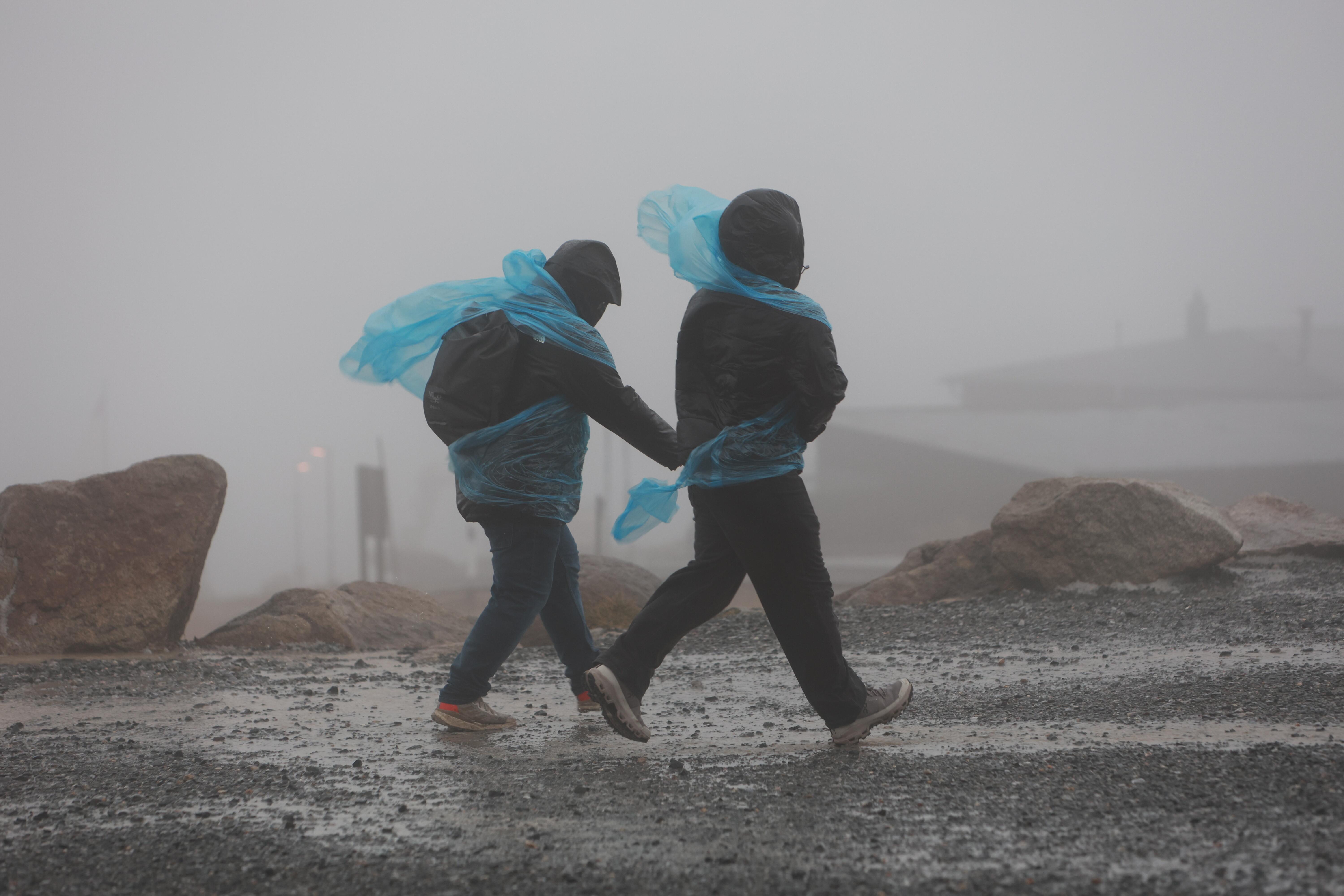 Wanderer gehen am Donnerstag auf dem Brocken entlang. Mit über 100 km/h erreichen die ersten Vorboten des Sturmtief "Joshua" den Harz.