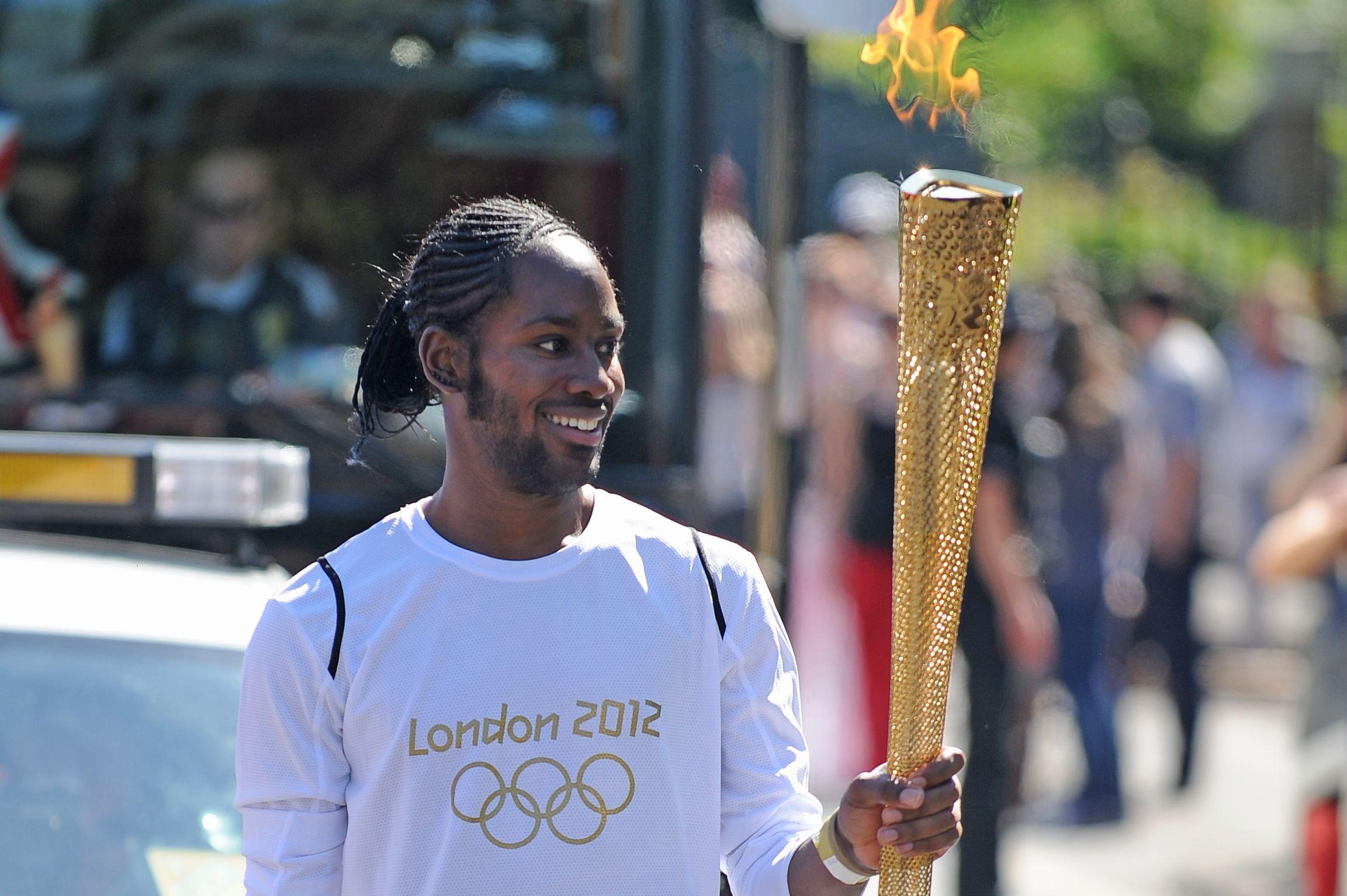 ARCHIV - 23.07.2012, Großbritannien, London: Jason Arday, trägt die olympische Fackel auf der Etappe des Fackellaufs