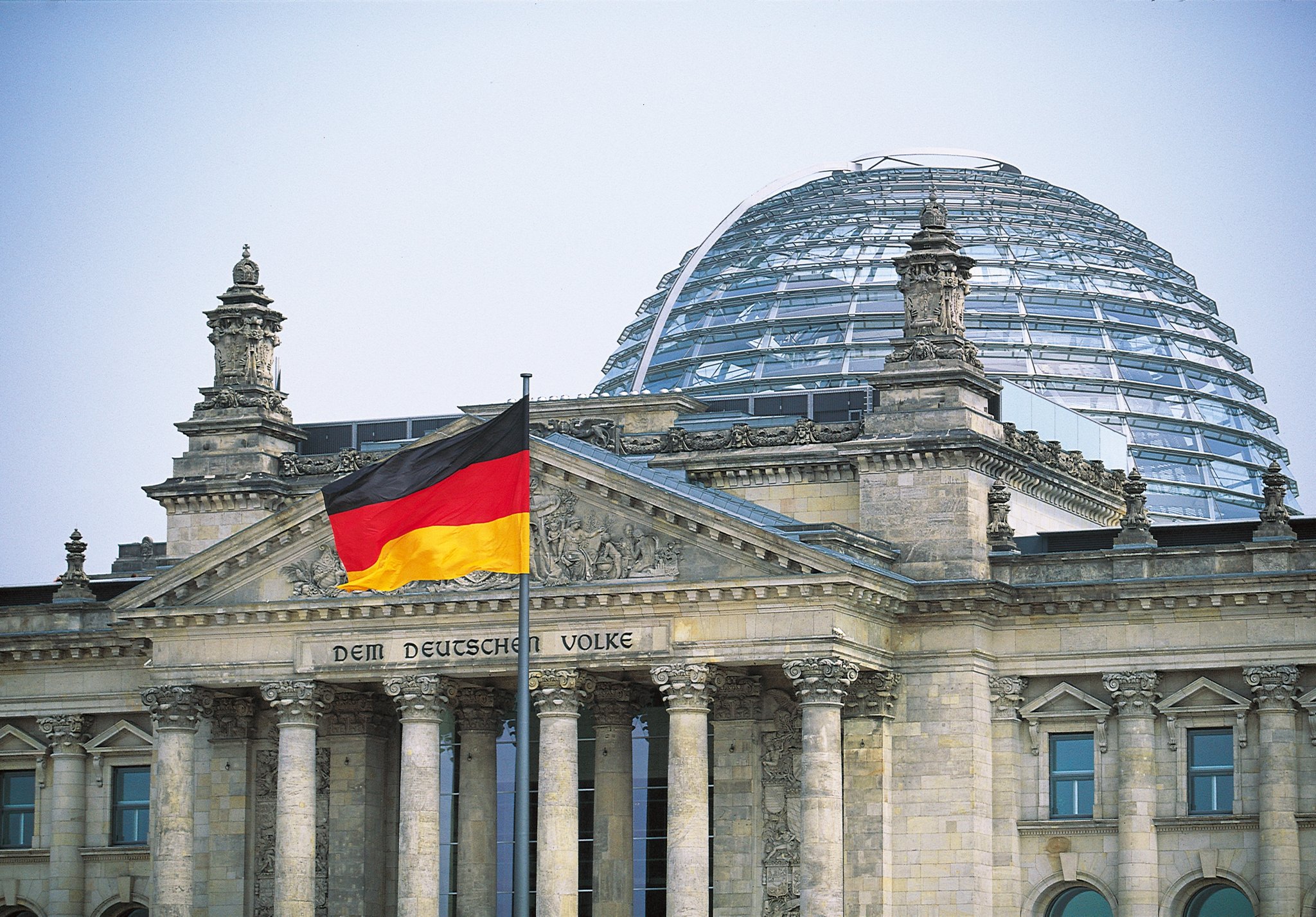 Reichstag in Berlin mit wehender deutscher Flagge.