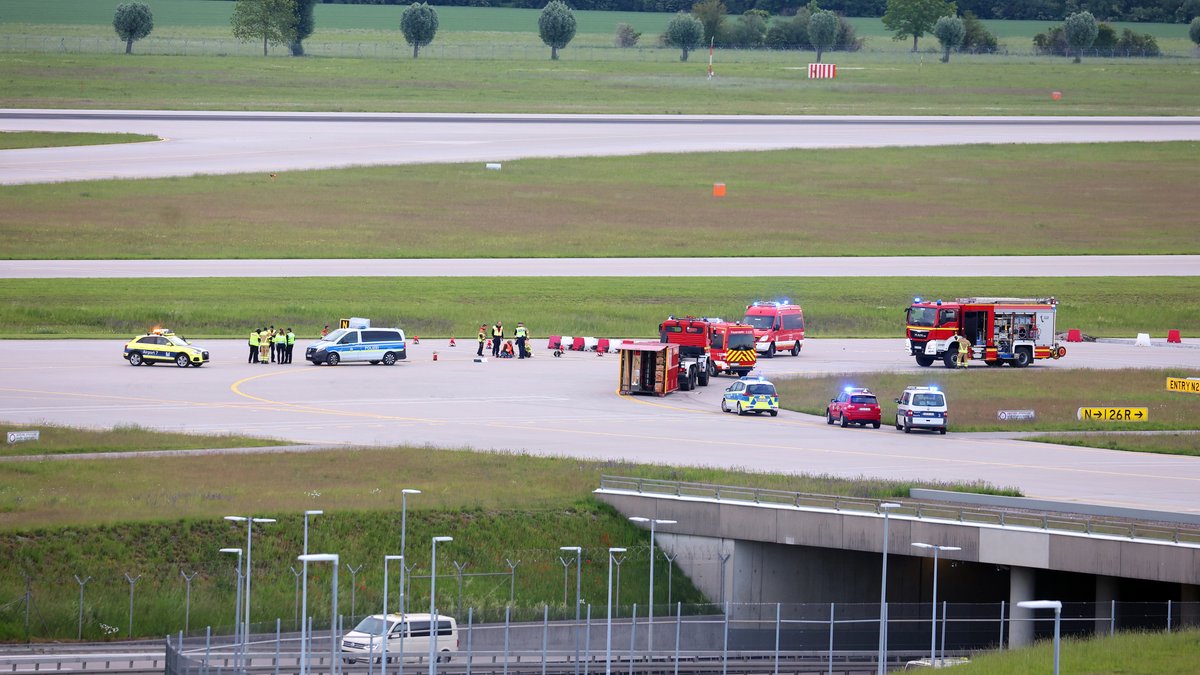 Einsatzkräfte von Polizei und Feuerwehr stehen auf einer Zufahrt für Start- und Landebahnen am Flughafen Franz-Josef-Strauß um Klimaaktivisten die sich dort festgeklebt haben. Klimaschutzaktivisten haben am frühen Morgen des 18. Mai 2024 den Münchner Flughafen lahmgelegt. Die Aktivisten waren in den inneren Bereich des Airport-Geländes gelangt. Mitglieder der sogenannten Letzten Generation hatten nach eigenen Angaben geplant, auf das Gelände des Flughafens zu gelangen, um mindestens eine der beiden Start- und Landebahnen zu blockieren.