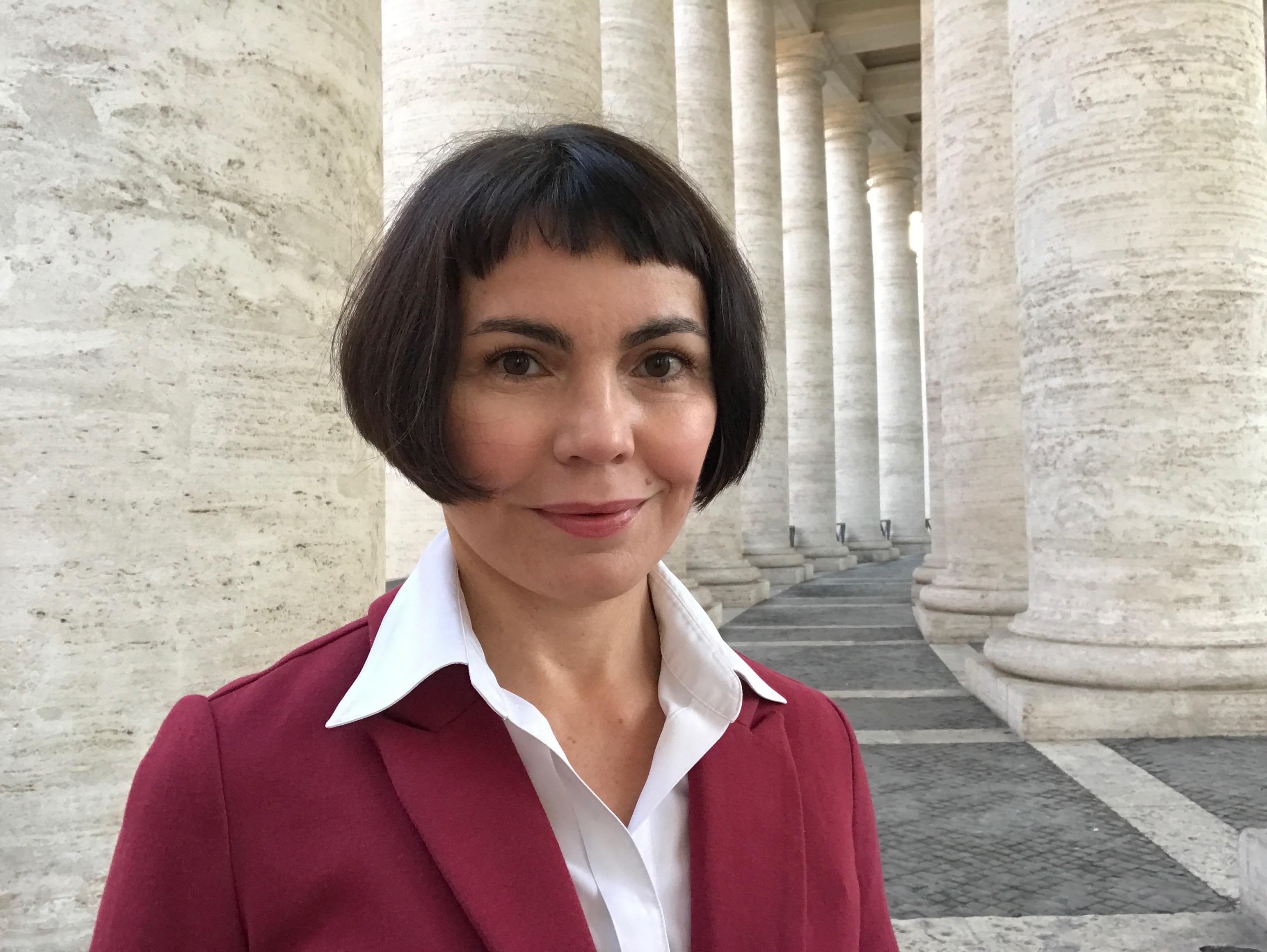 Eine Frau mit Pagenkopf, weißem Hemd und rotem Blazer: es ist Gudrun Sailer