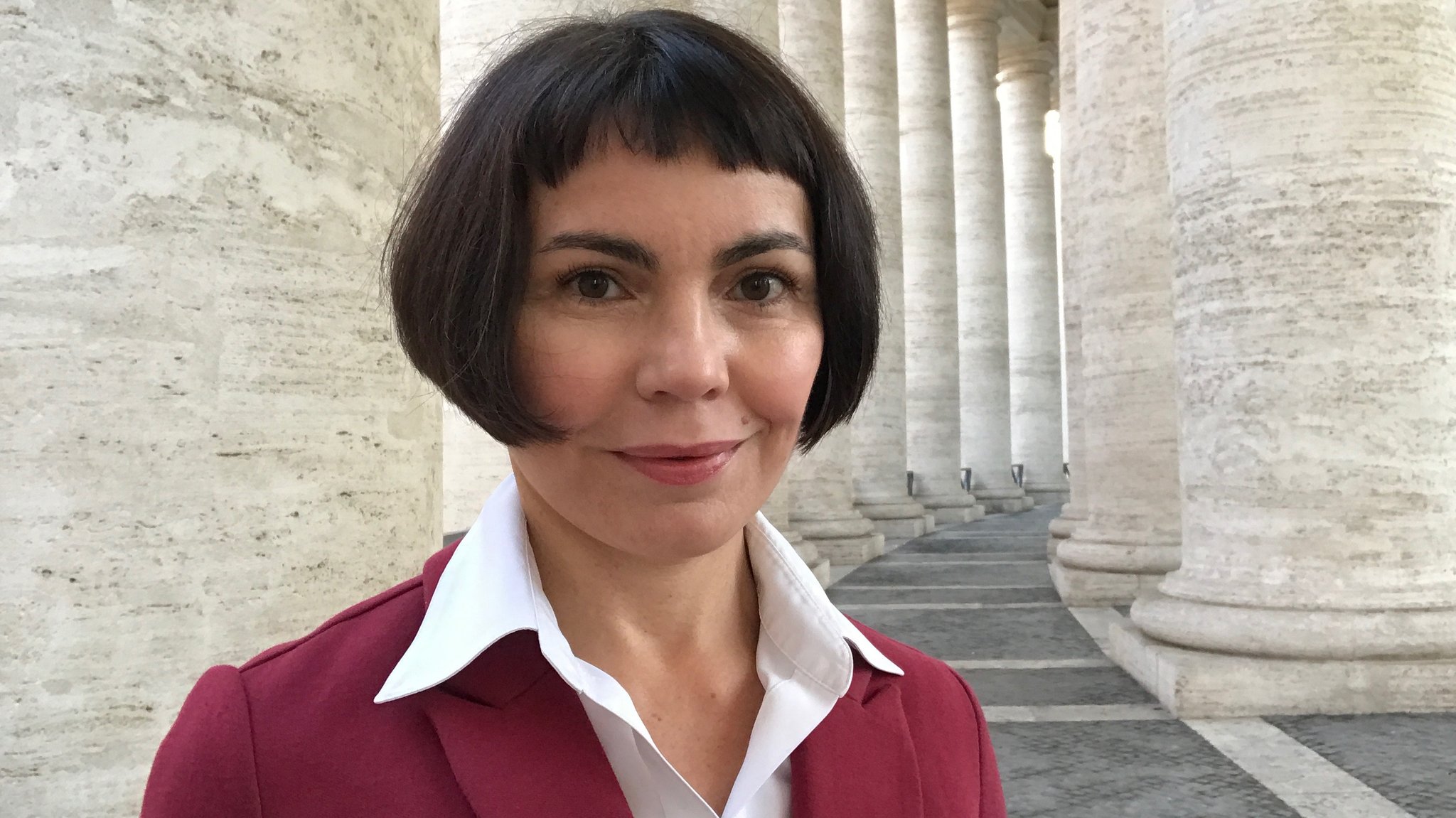 Eine Frau mit Pagenkopf, weißem Hemd und rotem Blazer: es ist Gudrun Sailer