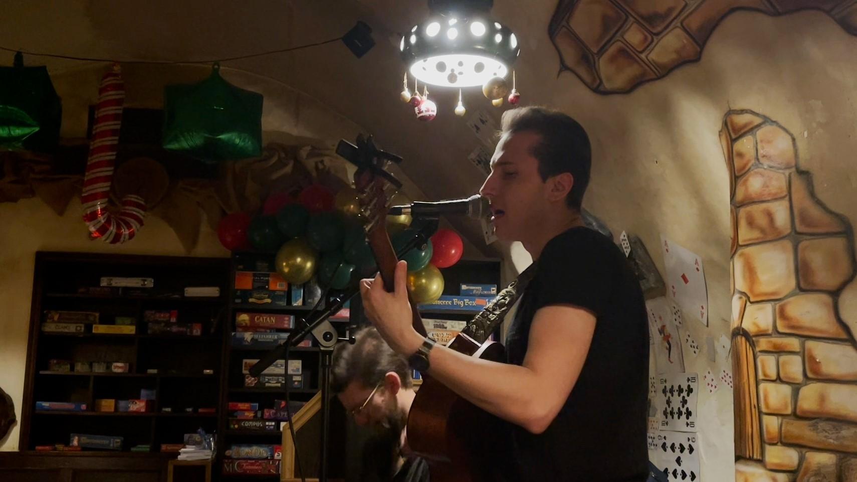 Ein junger Mann singt und spielt Gitarre.