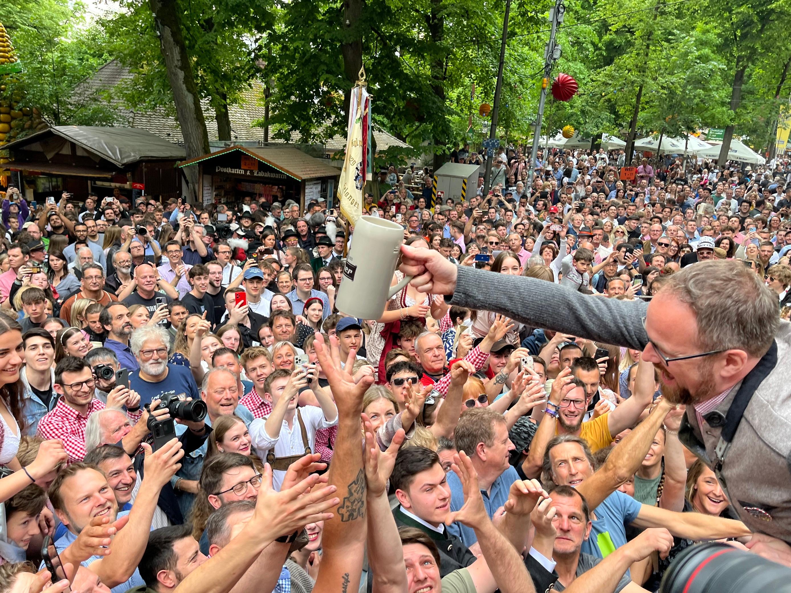 Erlangens Oberbürgermeister Florian Janik verteilt nach dem Anstich Freibier in die Menge.