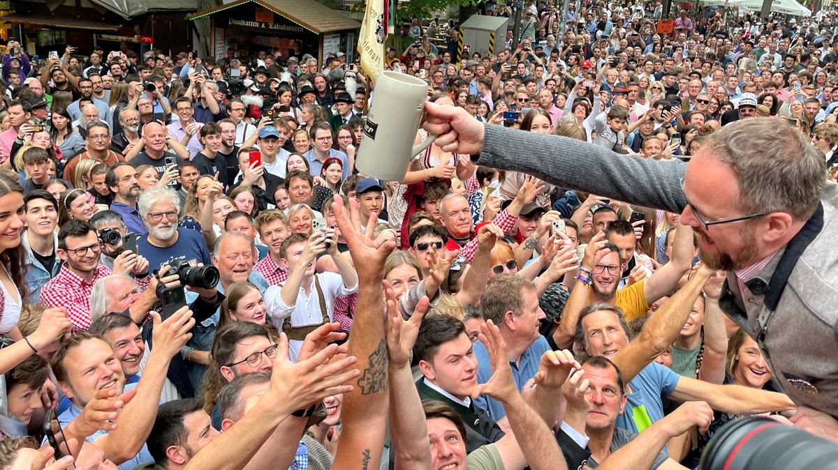Erlangens Oberbürgermeister Florian Janik verteilt nach dem Anstich Freibier in die Menge.