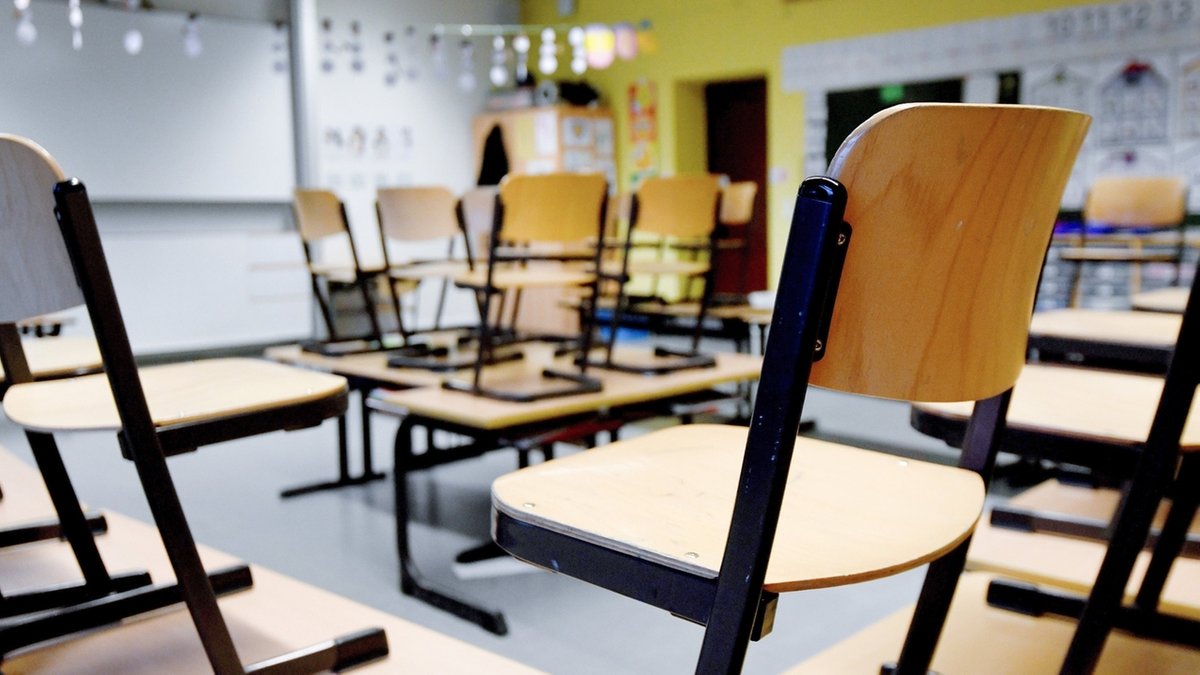 Stühle stehen in einem Klassenzimmer in einer Grundschule auf den Tischen.
