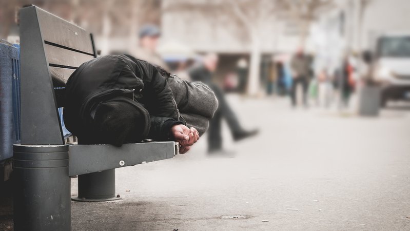 Obdachloser Mann schläft auf einer Parkbank (Symbolbild)