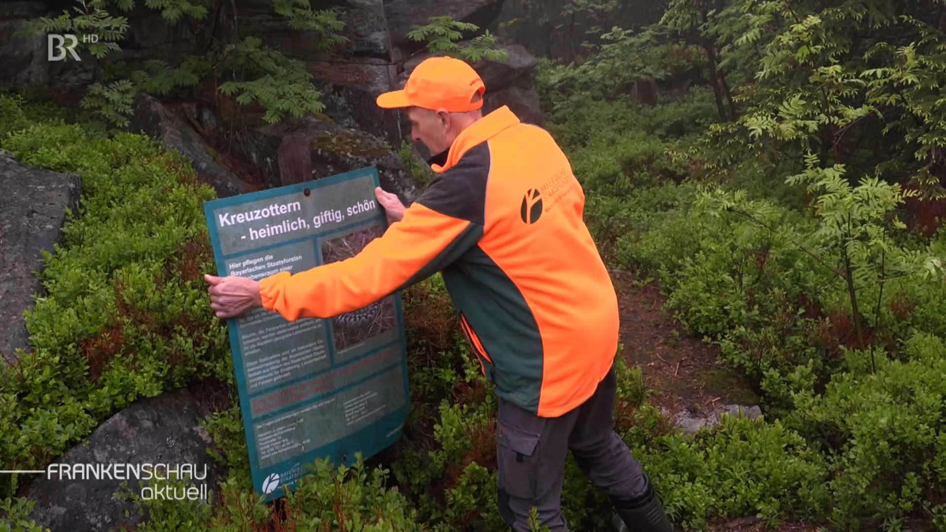 Mann stellt Hinweisschild auf.
