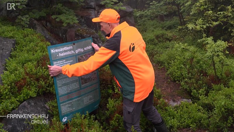 Mann stellt Hinweisschild auf. | Bild: BR Mann stellt Hinweisschild auf.