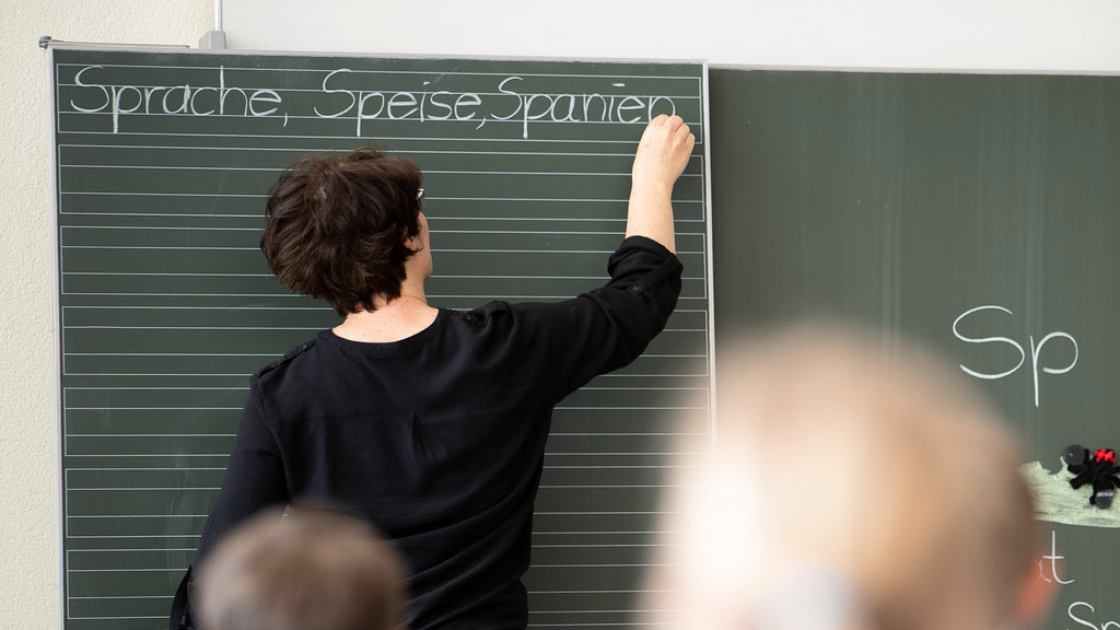 Eine Lehrerin schreibt in einer Schule Worte an eine Tafel. (Symbolbild)