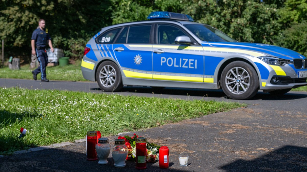 Polizeiauto und Kerzen am Tatort in Lohr am Main, einen Tag nach dem gewaltsamen Tod eines 14 Jahre alten Schülers