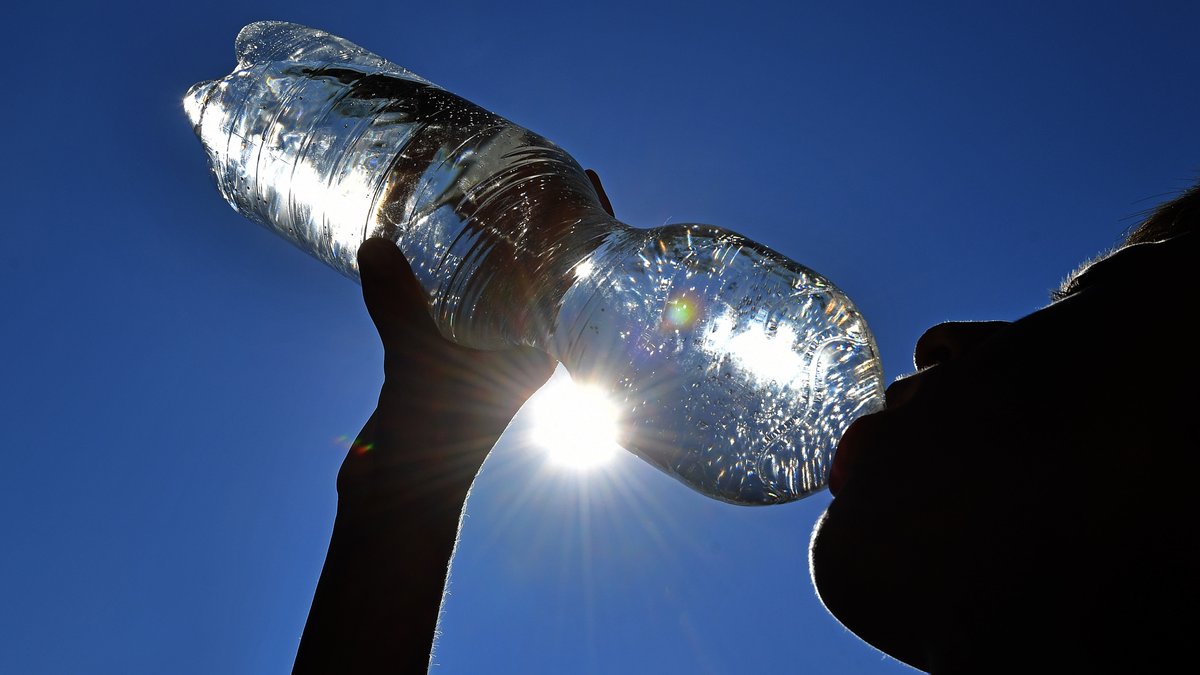 Ein Junge trinkt Wasser aus einer Plastikflasche bei großer Hitze (Symbolbild).