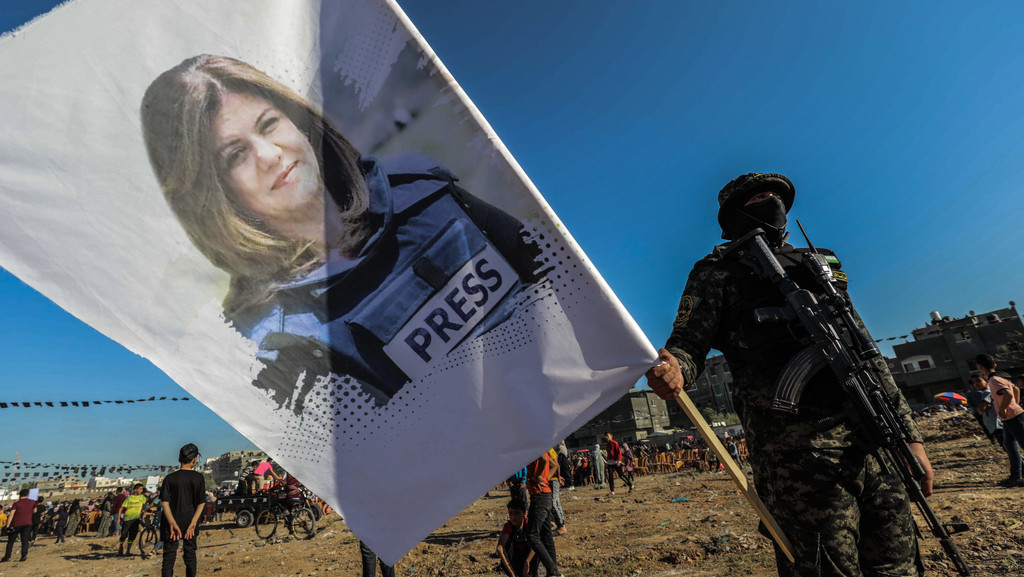 Ein palästinensischer Soldat hält eine Fahne mit dem Foto der palästinensisch-amerikanischen Al-Jazeera-Reporterin Shirin Abu Akle, die im Mai 2022 im Westjordanland wohl von israelischen Soldaten erschossen worden ist.