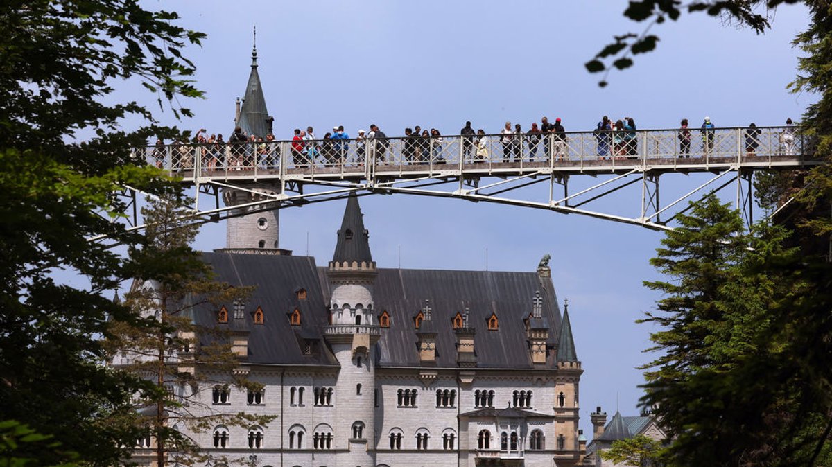 Touristen blicken auf Schloss Neuschwanstein