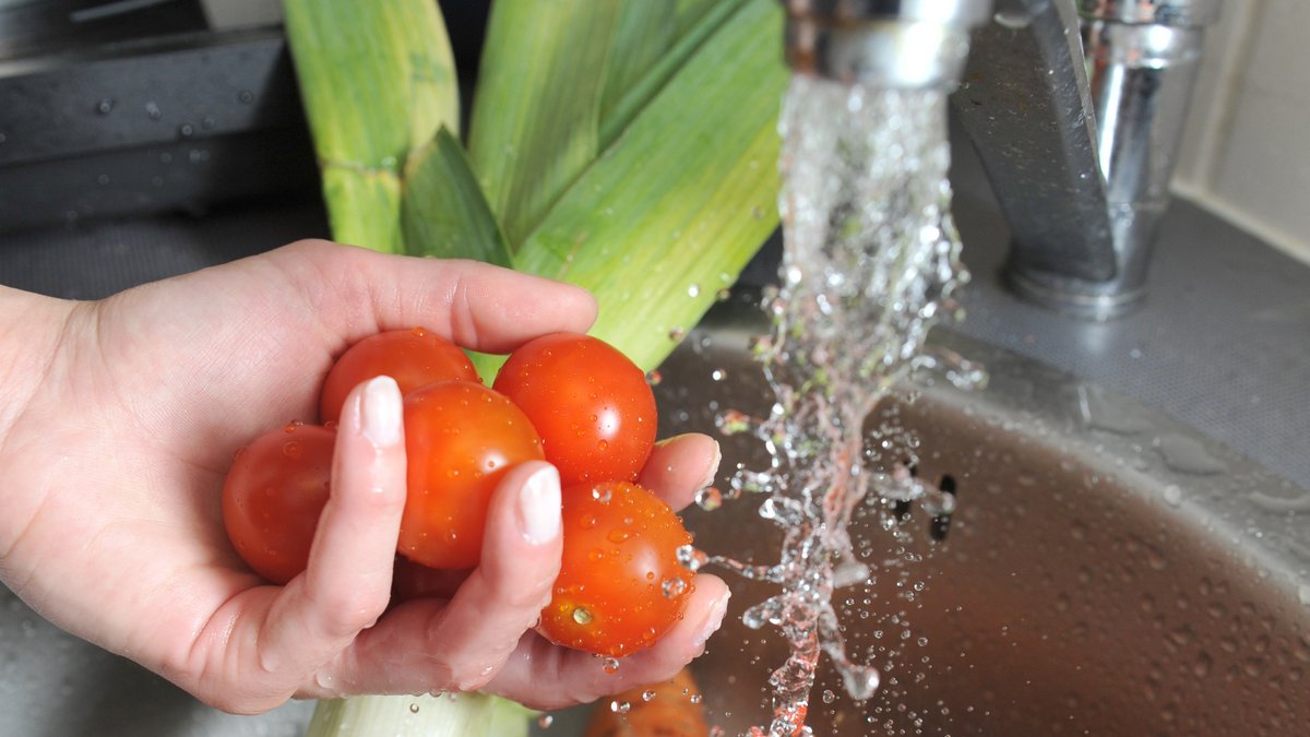 Gemüse wird unter einem Wasserhahn gewaschen