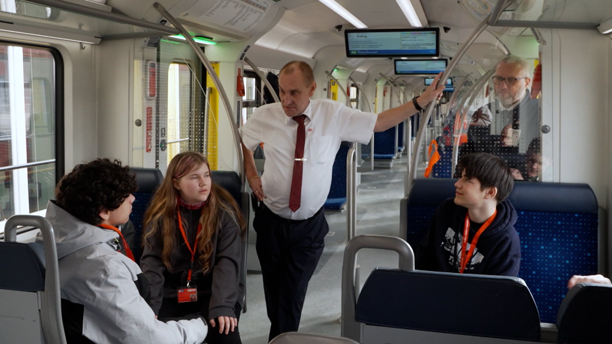 Jugendliche sitzen mit Ausbilder in einer S-Bahn