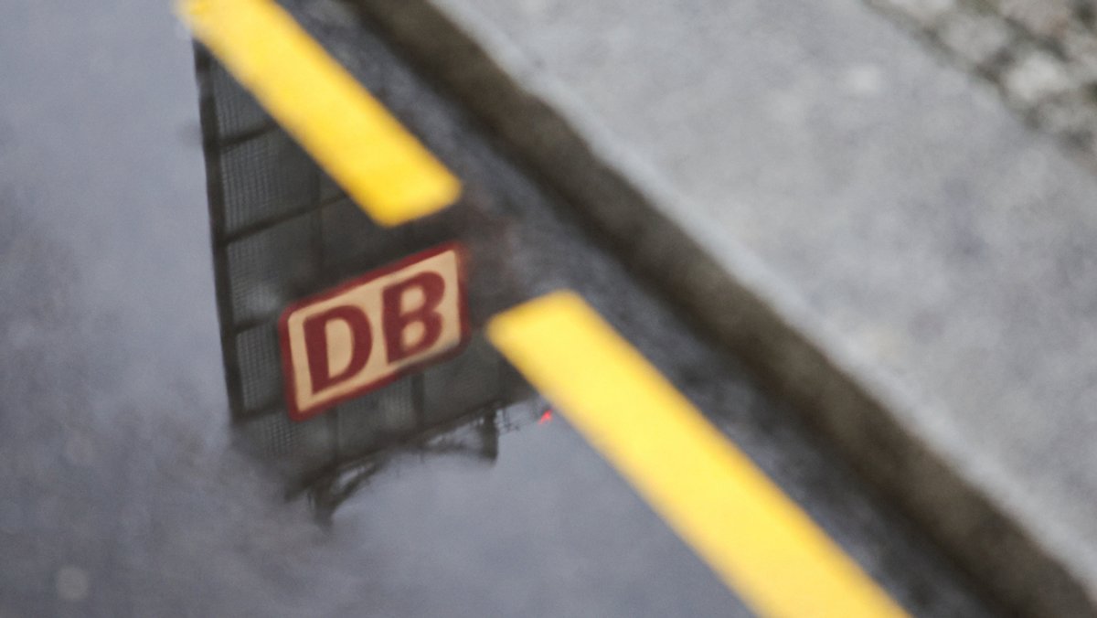 in Logo der Deutschen Bahn spiegelt sich in einer Pfütze vor dem Berliner Hauptbahnhof. 
