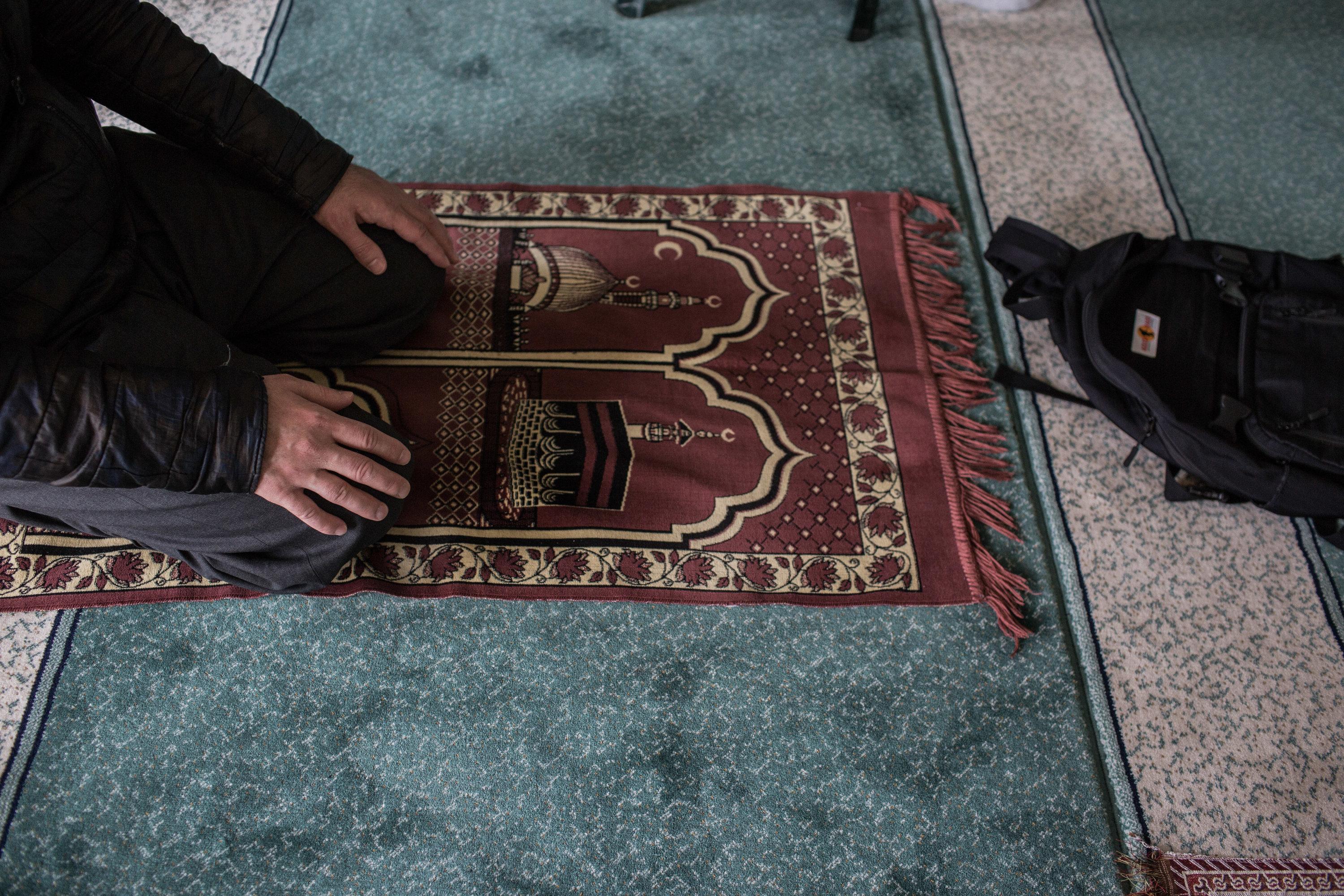 Ein Muslim kniet während eines Gebets auf einem Gebetsteppich in einer Moschee.