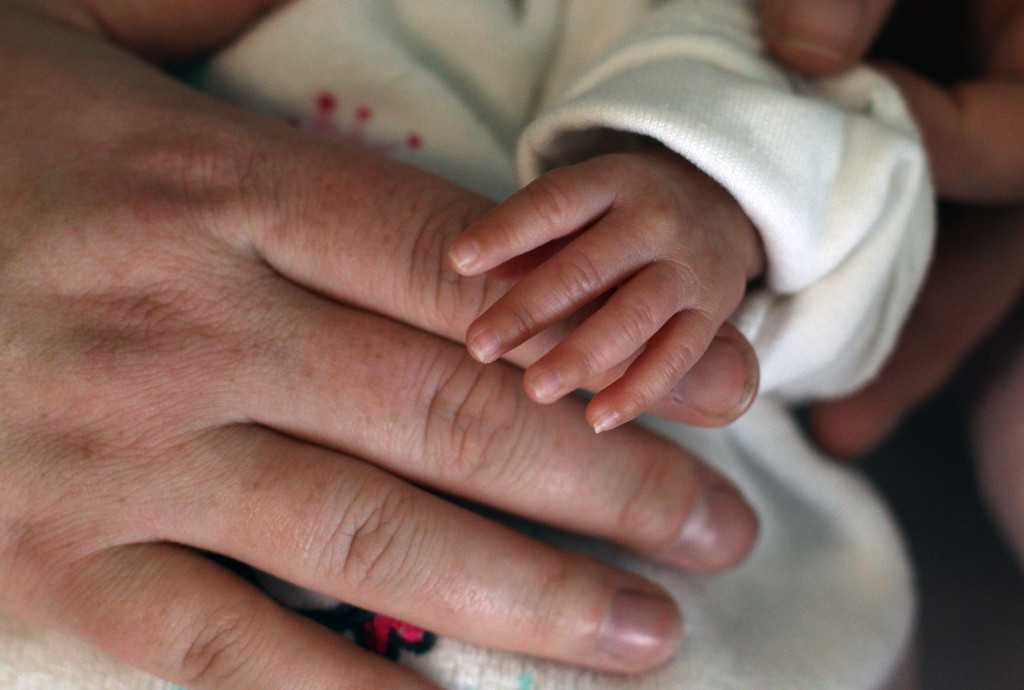 Mutter hält die Hand ihres neugeborenen Kindes
