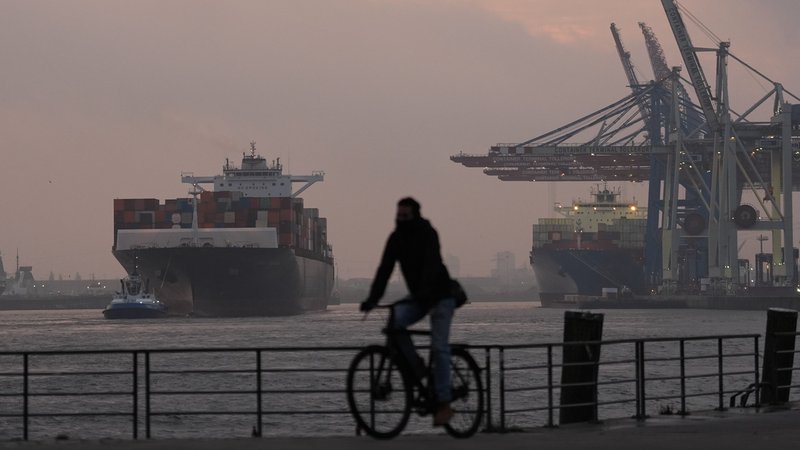 Zu sehen ist ein Containerschiff im Hamburger Hafen. Ein Fahrradfahrer fährt entlang der Promenade. | Bild: dpa-Bildfunk/Marcus Brandt Zu sehen ist ein Containerschiff im Hamburger Hafen. Ein Fahrradfahrer fährt entlang der Promenade.
