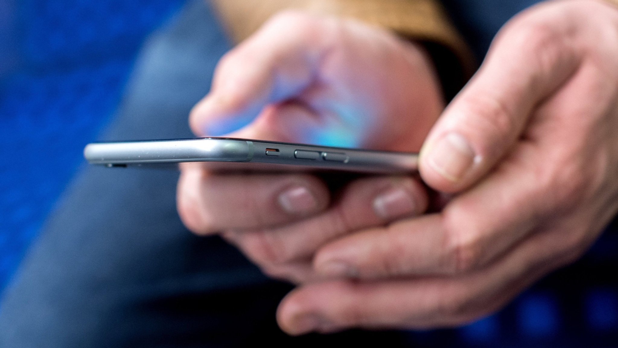 Ein junger Mann sitzt in einer S-Bahn und benutzt sein Smartphone.