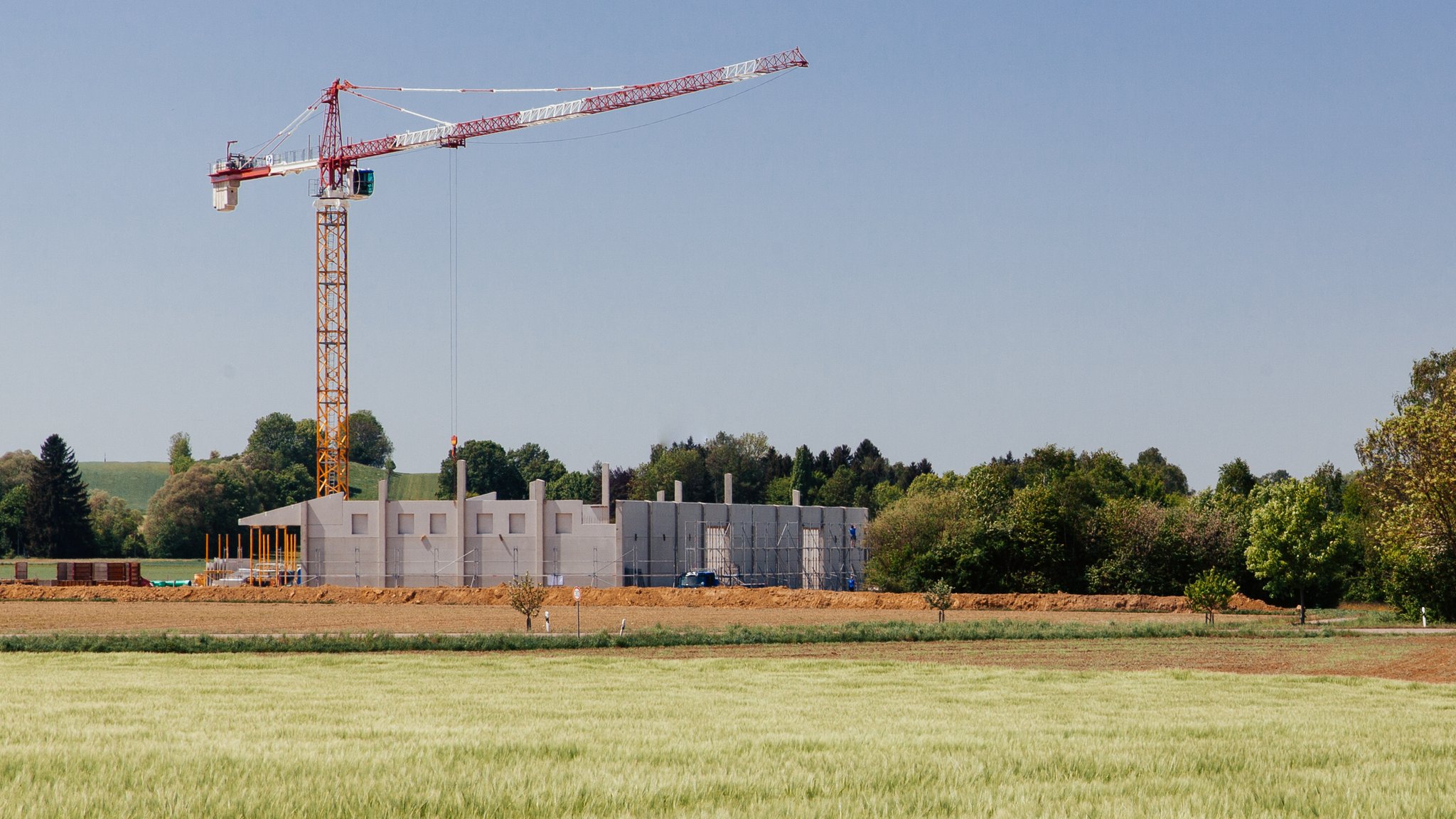 Ein Gebäude aus  Beton wird am Rande eines Kornfeldes errichtet.