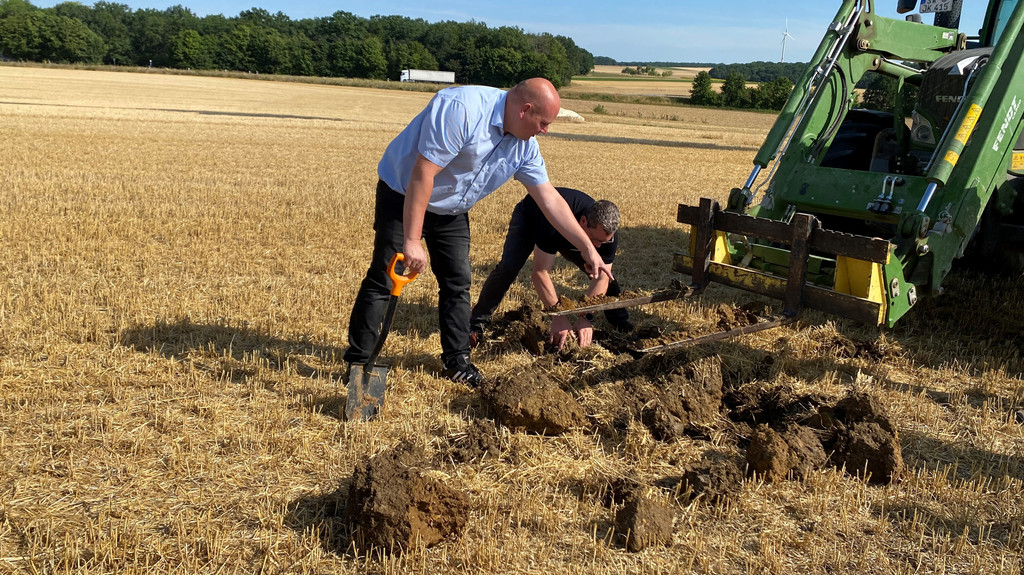 Landwirt Jochen Klein und Bezirkspräsident des Bayerischen Bauernverbands Stefan Köhler begutachten den trockenen Ackerboden.