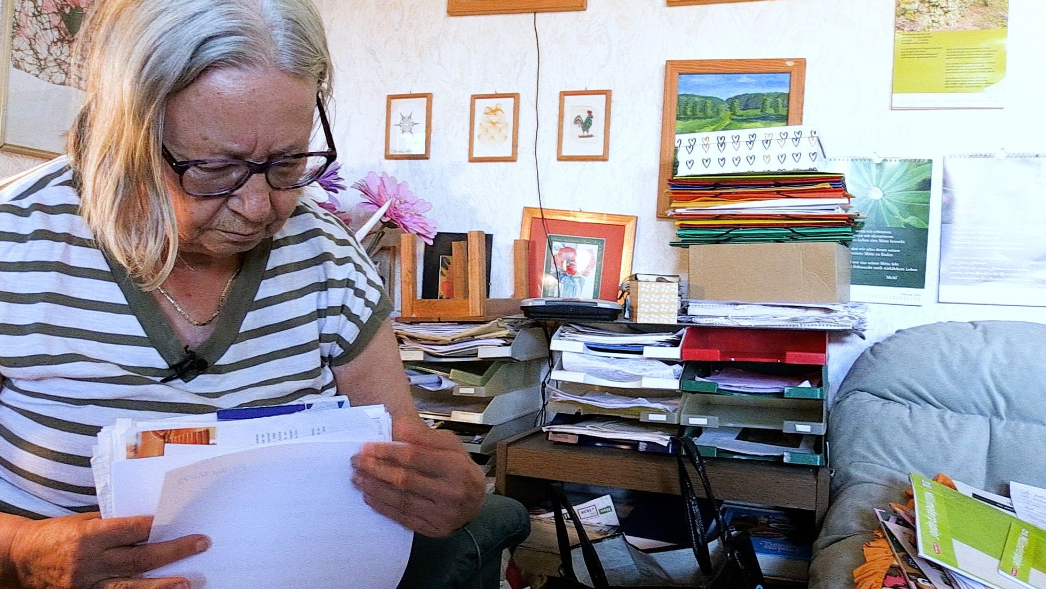 Margarete Rodamer mit einem Stapel Zetteln in der Hand in ihrem Wohnzimmer.