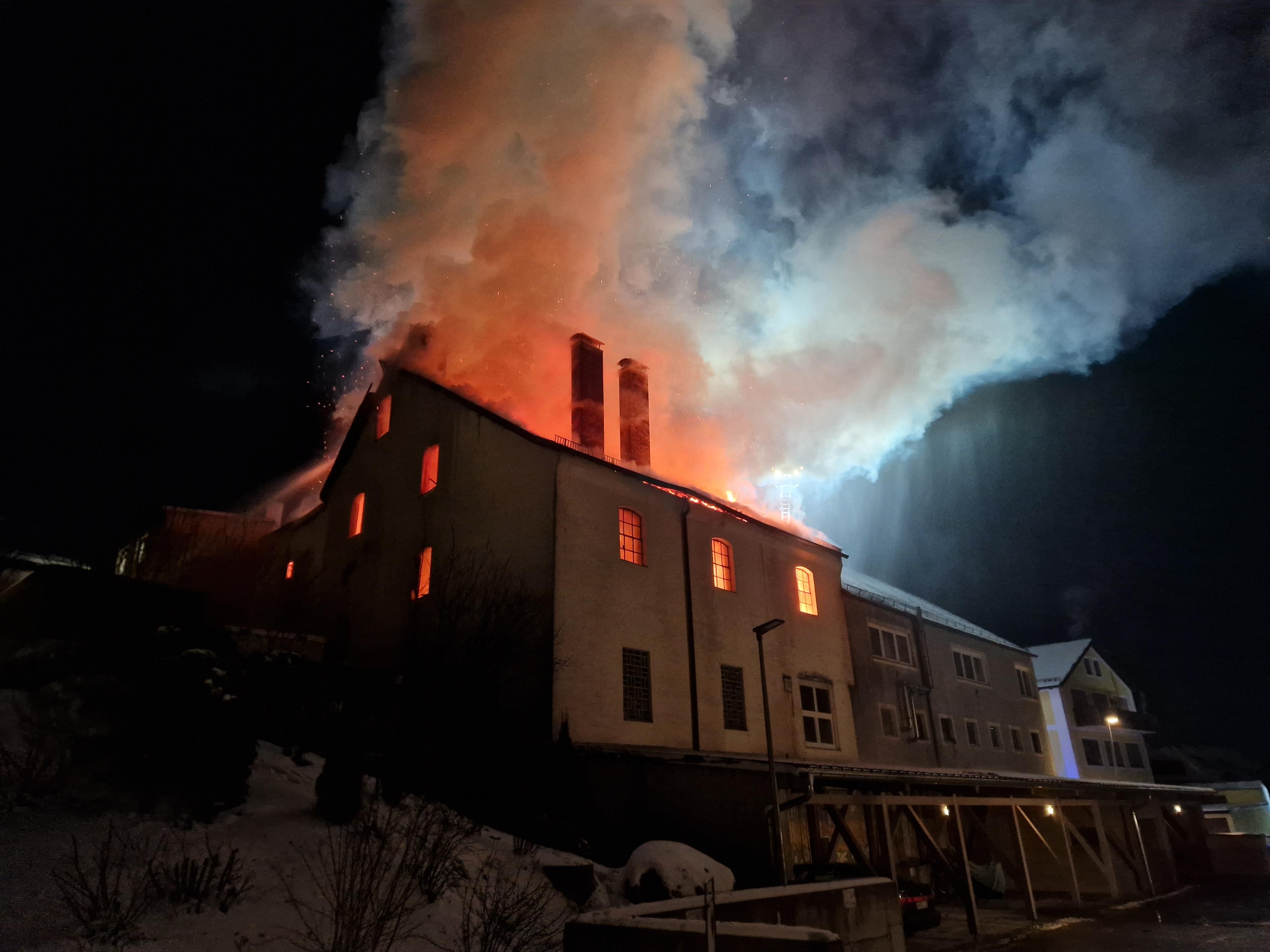 Aus dem Wohn- und Geschäftsgebäude schlagen Flammen.