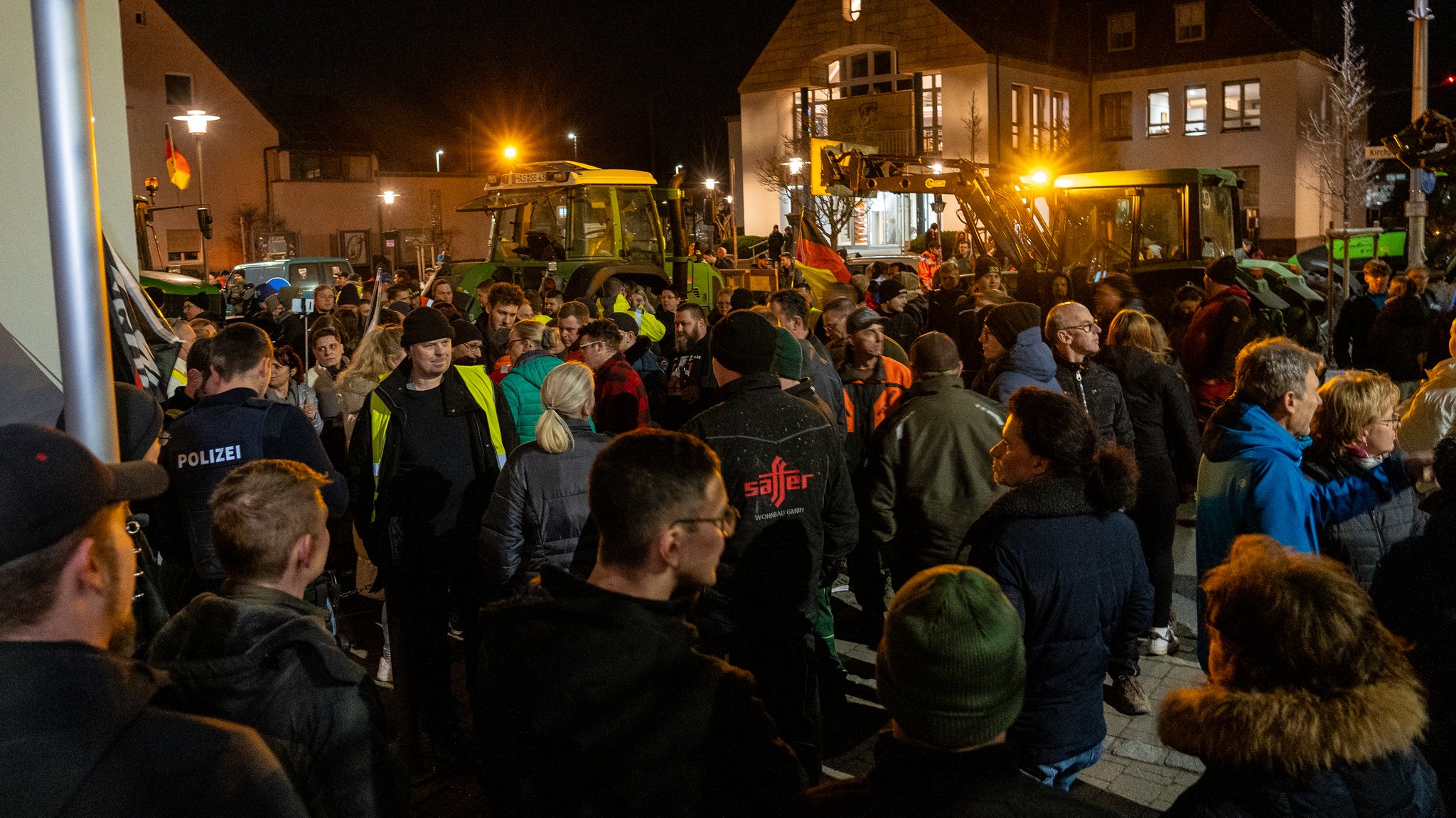 Protestierende Menschen stehen in Hirschaid. Im Hintergrund sind Traktoren zu sehen. Auch zwei Deutschlandfahnen werden geschwenkt. 