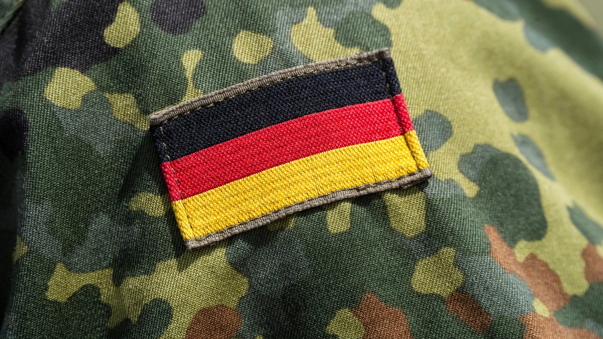 Flecktarnmuster auf der Uniform eines Bundeswehrsoldaten, mit Deutschlandflagge als Aufnäher auf dem Ärmel