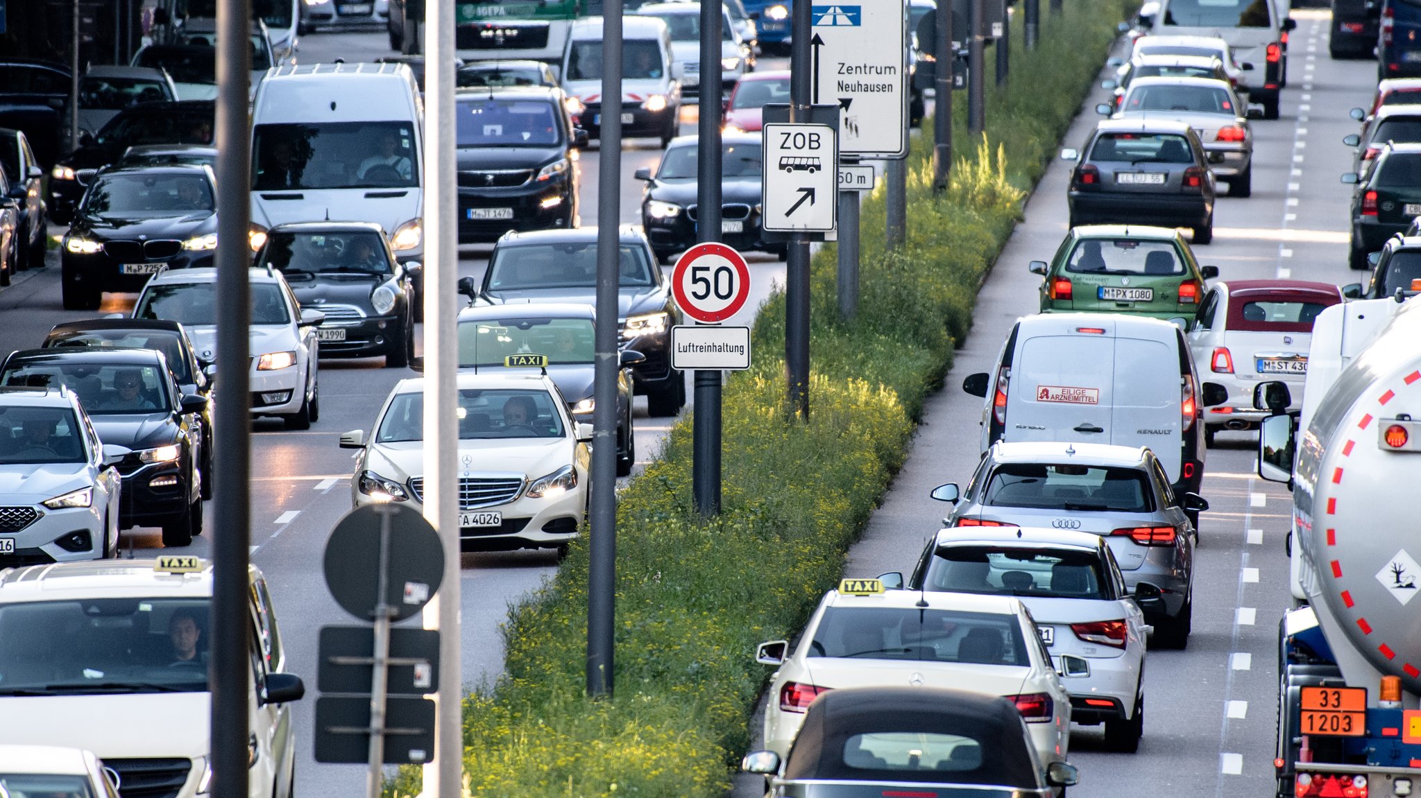 Dichter Verkehr schiebt sich über den Mittleren Ring. In der Mitte der Straße steht ein Schild mit der Aufschrift "Luftreinhaltung".