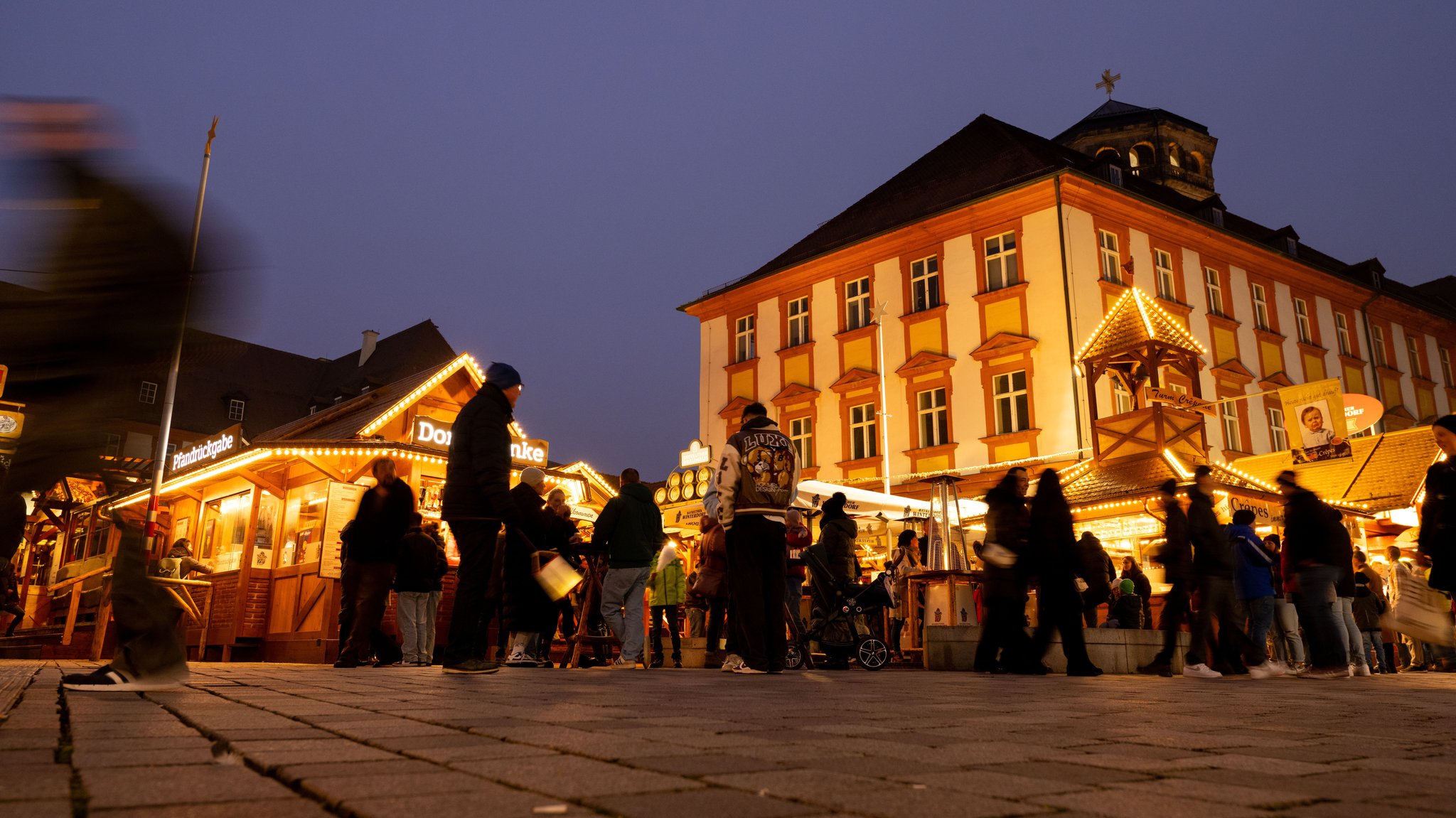 Menschen tummeln sich im Bayreuther Winterdorf. Die Stadt hat als Klimaschutzmaßnahme ihre Weihnachtsbeleuchtung auf LED umgerüstet.