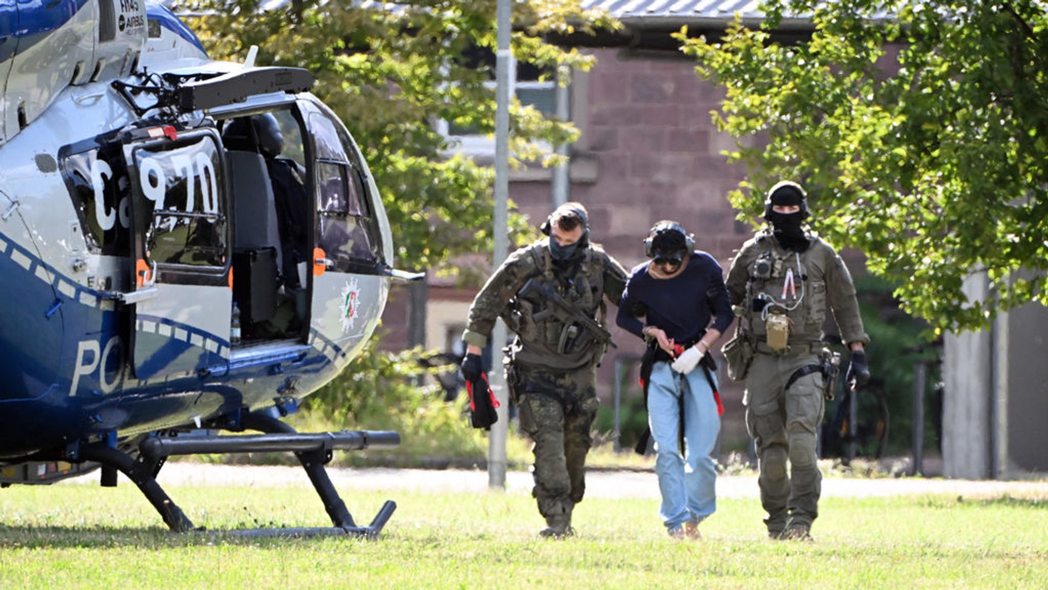 25.08.2024, Baden-Württemberg, Karlsruhe: Der mutmassliche Täter des Messerangriffs von Solingen wird zu einem Hubschrauber gebracht. Zuvor war der Verdächtige dem Ermittlungsrichter beim Bundesgerichtshof (BGH) vorgeführt worden, der Haftbefehl erlassen hat. Foto: Uli Deck/dpa +++ dpa-Bildfunk +++