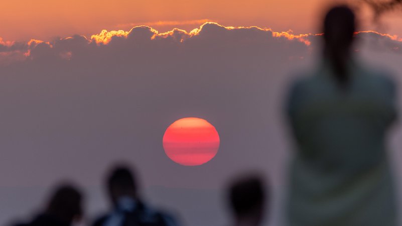 Menschen beobachten die Sonne am Horizont (Symbolbild)