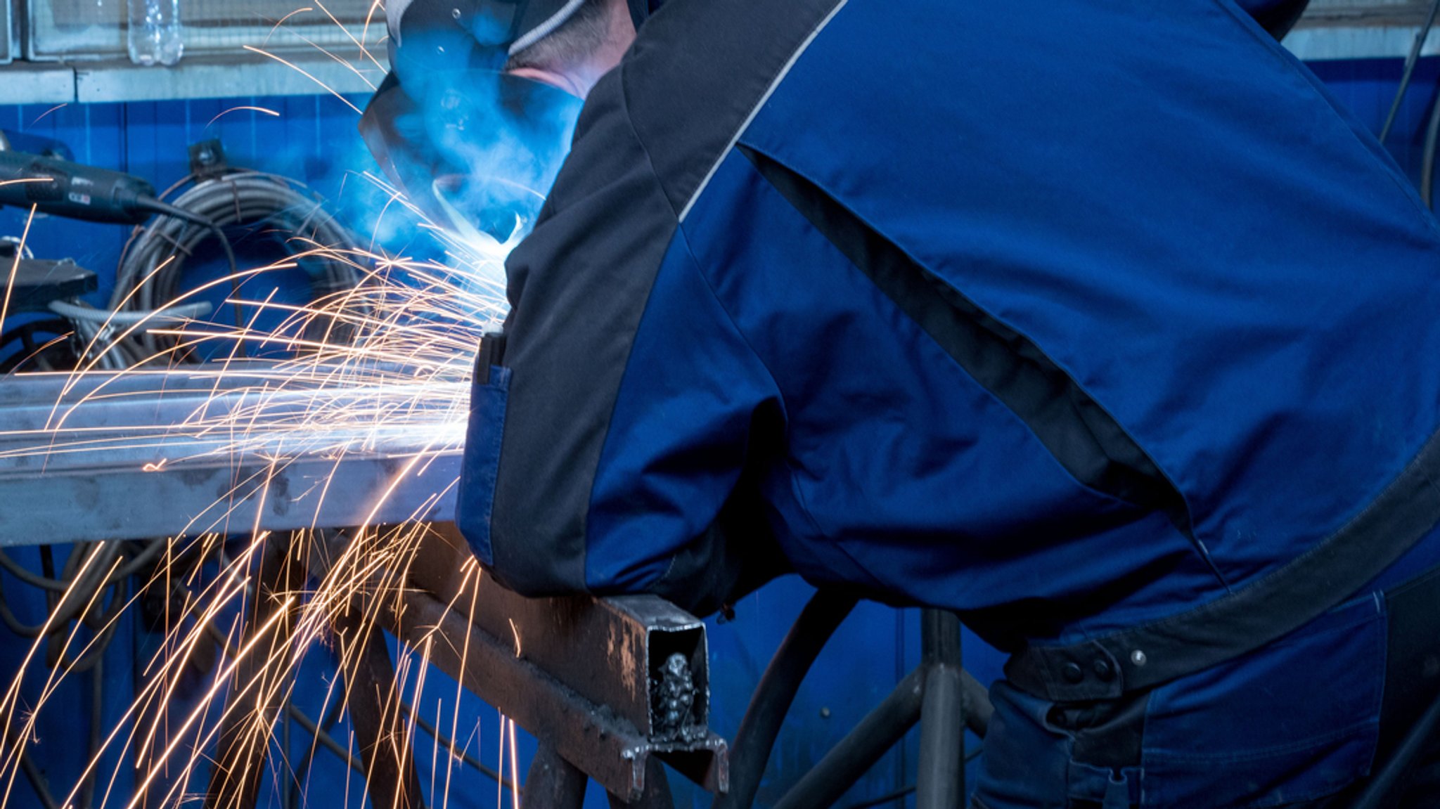 Ein Schweißer arbeitet in der Werkhalle eines Metallbauunternehmens