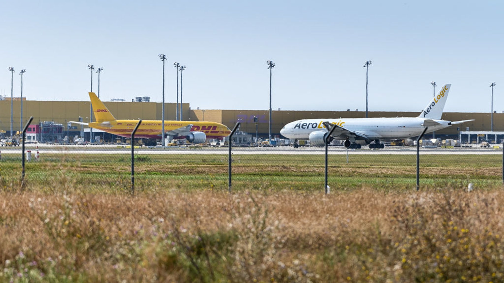 30.08.2024, Sachsen, Schkeuditz: Flugzeuge vor dem DHL Air Hub, dem Luftfrachtzentrum auf dem Flughafen Leipzig / Halle. Deutsche Sicherheitsbehörden warnen vor «unkonventionellen Brandsätzen», die von Unbekannten über Frachtdienstleister verschickt werden. In Sicherheitskreisen wird ein Zusammenhang mit russischer Sabotage nicht ausgeschlossen. Foto: Heiko Rebsch/dpa +++ dpa-Bildfunk +++