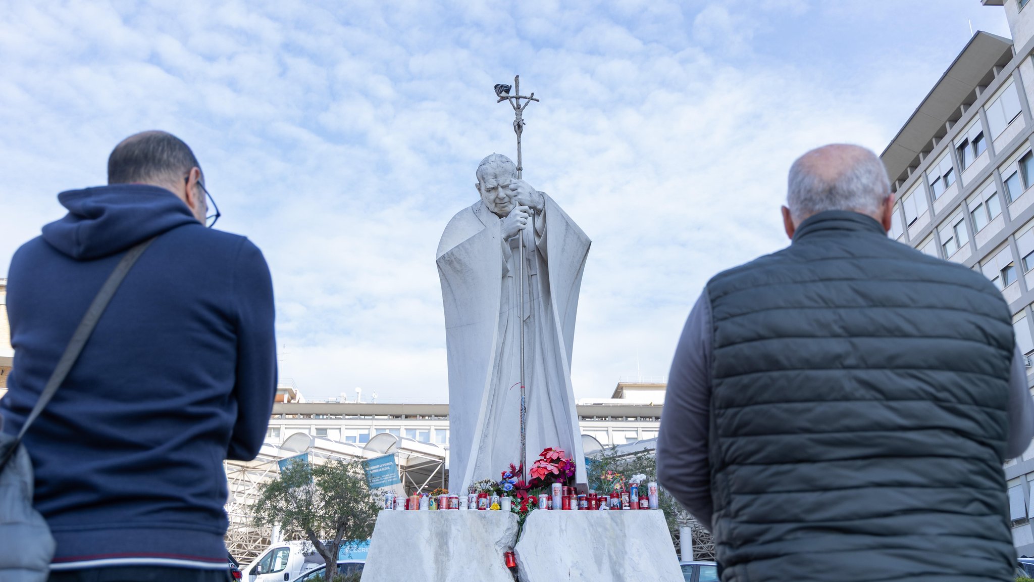 Gläubige beten für Papst Franziskus unter dem Denkmal von Papst Johannes Paul II. im Gemelli-Krankenhaus in Rom.