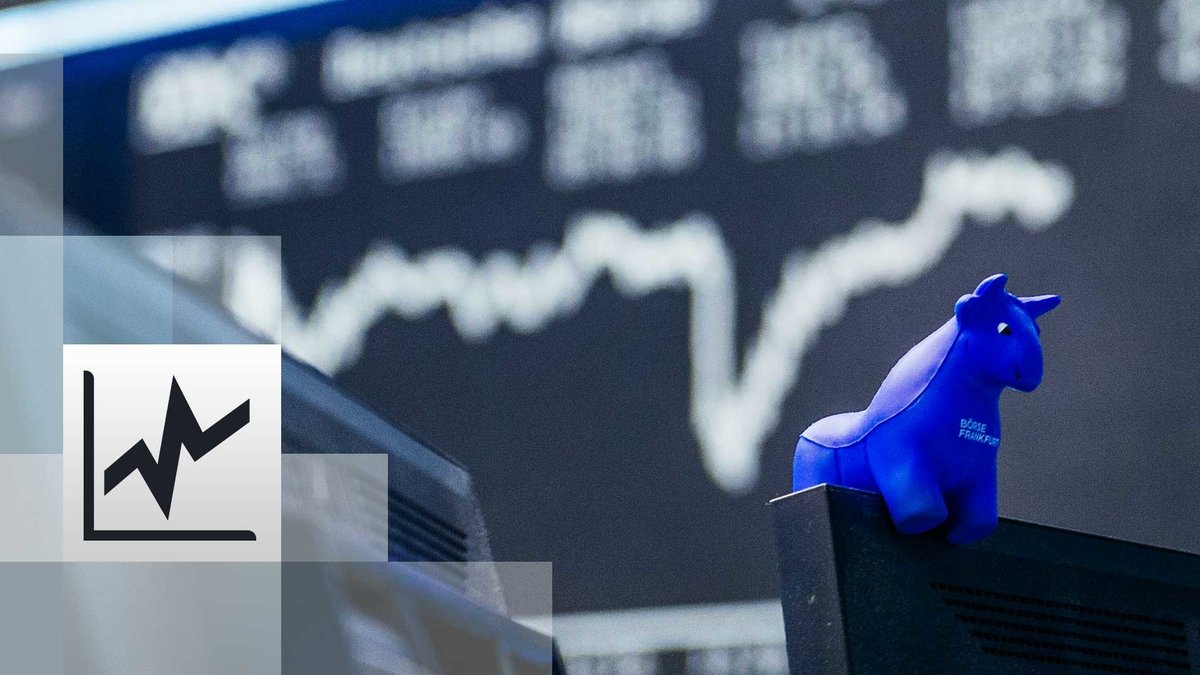 in blauer Stier aus Gummi sitzt auf der oberen Kante eines Bildschirmes, im Hintergrund die Kurstafel der Börse