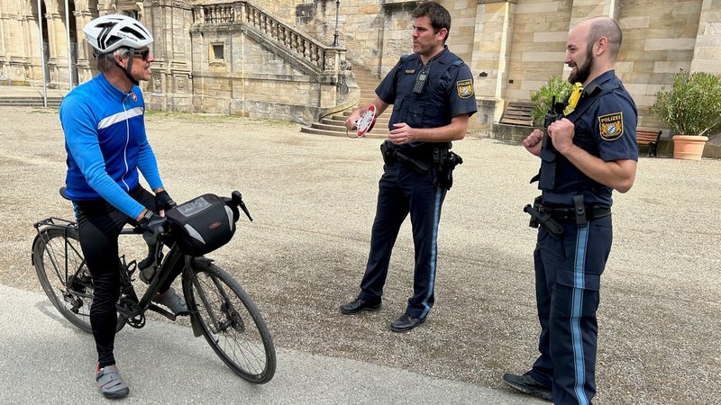 Ein Fahrradfahrer steht in Coburg neben zwei Polizisten.