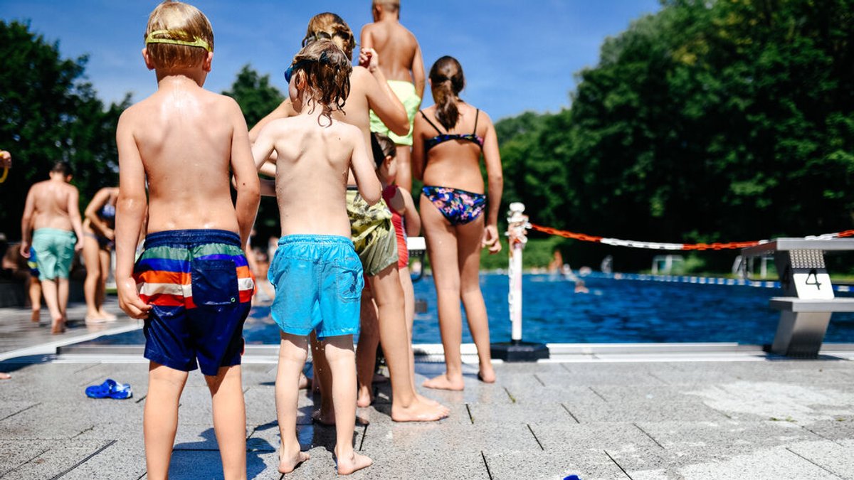 Kinder stehen im Schwimmbad am Beckenrand an.