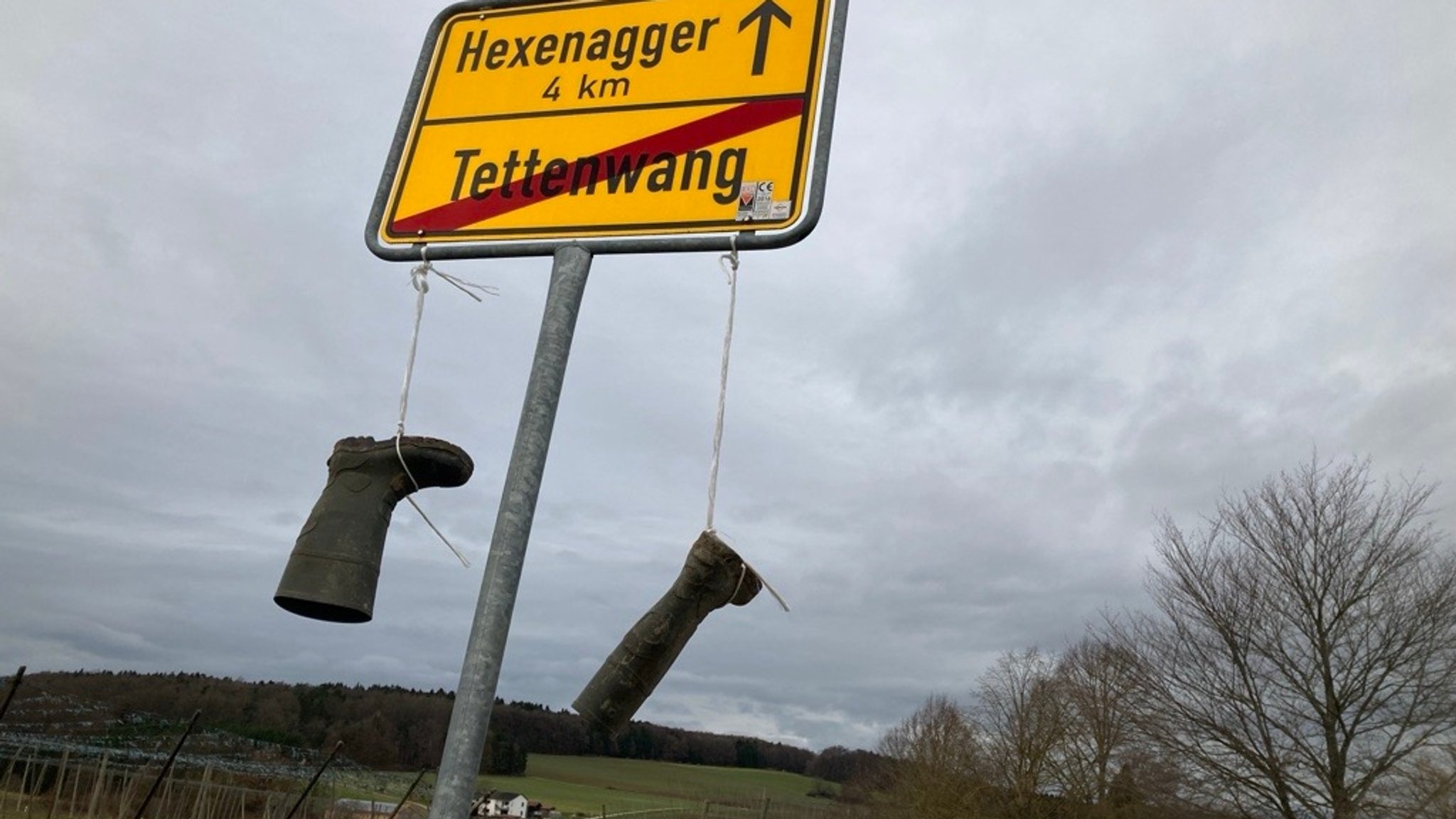 Gummistiefel hängen an einem Ortsschild 